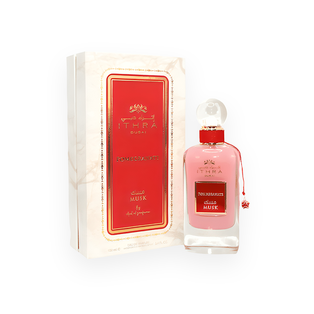 Packshot du parfum Pomegranate Musk 100 ml par Ithra Dubai, présenté dans un flacon rose élégant avec des détails dorés et un bouchon transparent en forme de boule, accompagné d'une boîte blanche marbrée ornée d'un encadrement rouge et doré, évoquant une fragrance fruitée et luxueuse.